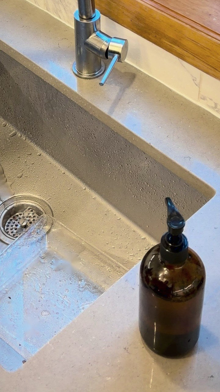 An amber glass pump bottle on the counter beside a kitchen sink